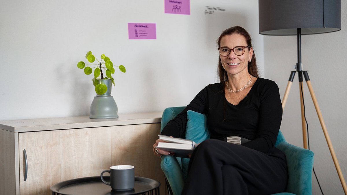 Petra Kuhlmann bei OVB Holding sitzt mit Buch im Büro