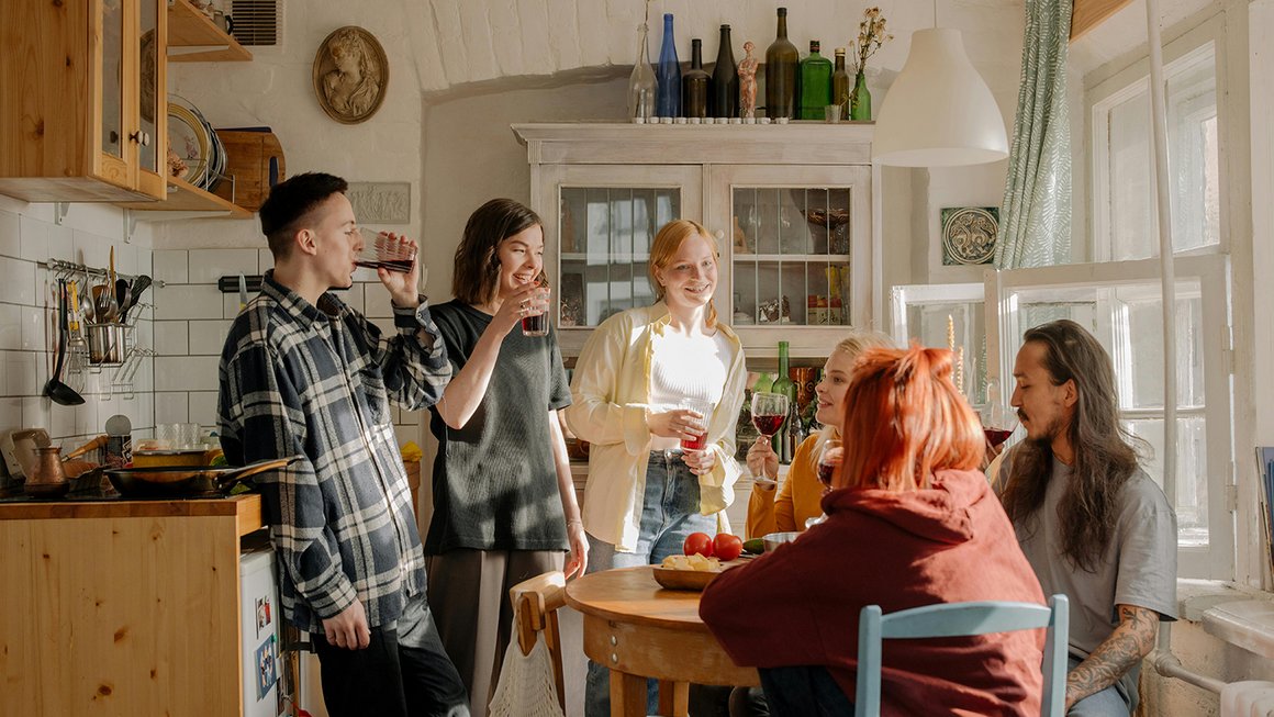 Eine Gruppe von jungen Leuten sitzt gemeinsam in der Küche 