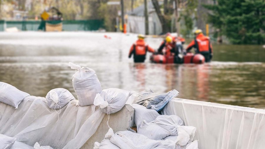 Unwetterschäden und ihre finanziellen Folgen Sandsäcke mit überfluteten Häusern und einem Rettungsteam im Hintergrund