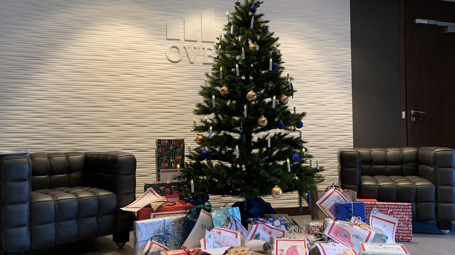 Geschmückter Weihnachtsbaum im Foyer der OVB Zentrale am Kölner Heumarkt. Vor dem Weihnachtsbaum liegen viele eingepackte Geschenke